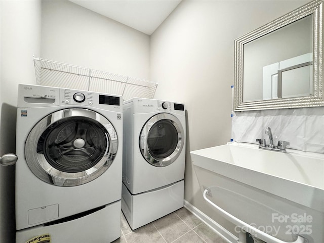 laundry area with laundry area, light tile patterned flooring, a sink, and washing machine and clothes dryer