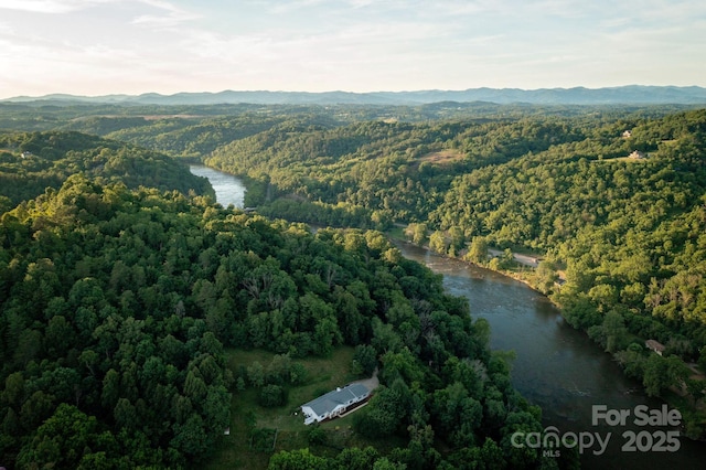 aerial view featuring a wooded view and a water and mountain view