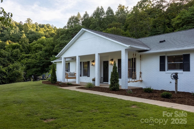 view of front of property with a porch, brick siding, a shingled roof, and a front lawn