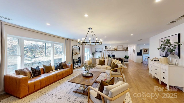 living room with an inviting chandelier, light wood-style flooring, visible vents, and recessed lighting