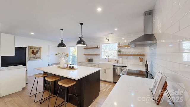 kitchen featuring dishwasher, wall chimney exhaust hood, light countertops, white cabinetry, and open shelves