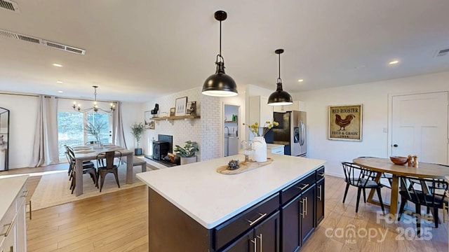 kitchen featuring light wood finished floors, a kitchen island, stainless steel refrigerator with ice dispenser, and light countertops