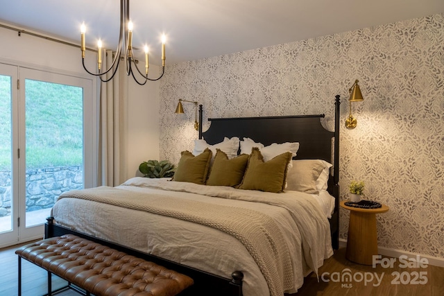 bedroom with access to exterior, multiple windows, wood finished floors, and wallpapered walls