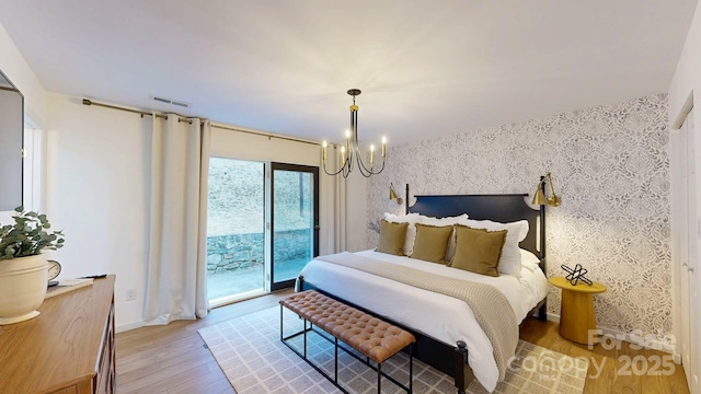 bedroom featuring wallpapered walls, light wood finished floors, visible vents, an accent wall, and access to exterior