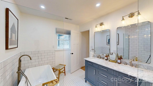 bathroom featuring visible vents, a sink, tile walls, and double vanity