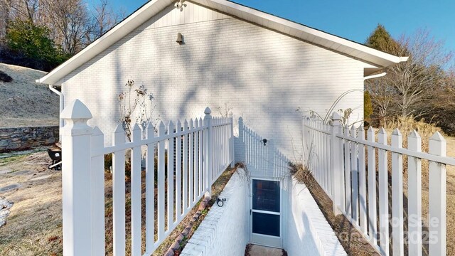 view of side of home with brick siding and fence