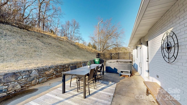 view of patio / terrace with a hot tub, a fenced backyard, and outdoor dining space