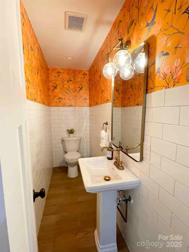 169 Chandler Rd, Alexander, NC 28701 - half bathroom with tile walls, wallpapered walls, toilet, wood finished floors, and wainscoting