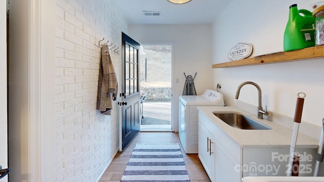 169 Chandler Rd, Alexander, NC 28701 - washroom with separate washer and dryer, cabinet space, light wood-type flooring, and brick wall