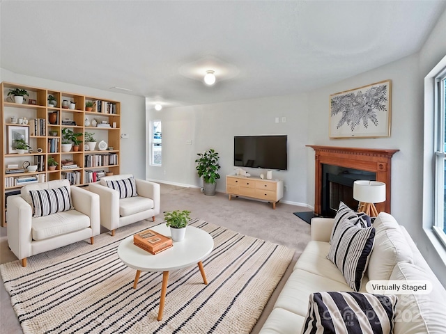 living area with a healthy amount of sunlight, carpet, baseboards, and a fireplace with raised hearth