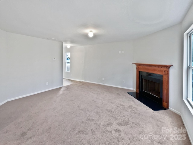 unfurnished living room with a fireplace, baseboards, and carpet flooring