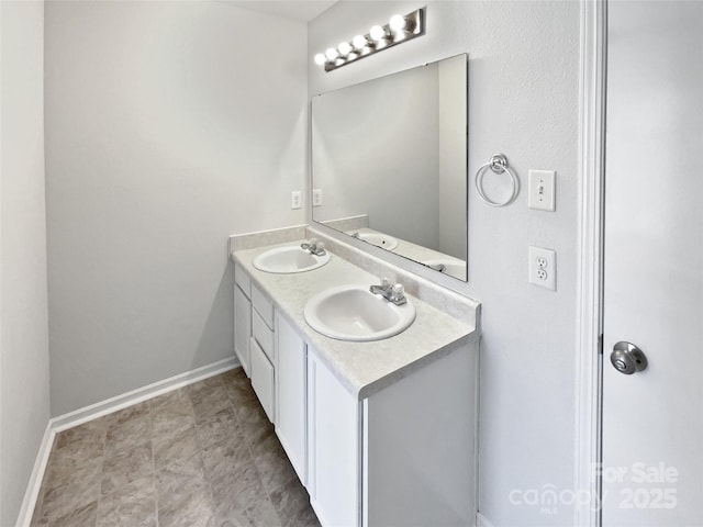 bathroom with a sink, baseboards, and double vanity