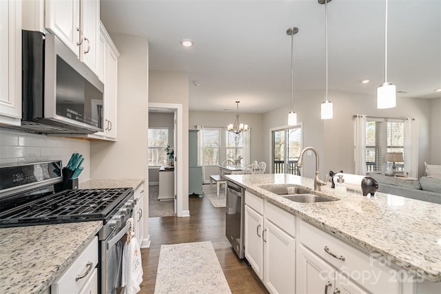14707 Batteliere Dr, Charlotte, NC 28278 - kitchen with decorative light fixtures, appliances with stainless steel finishes, white cabinets, a sink, and light stone countertops