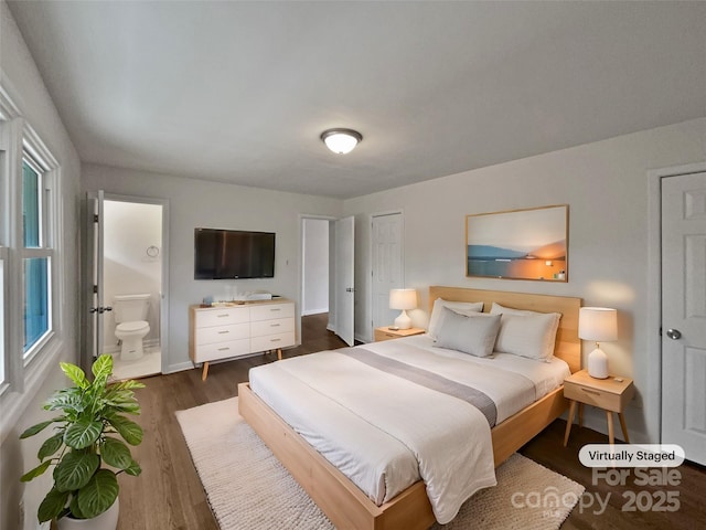 bedroom with connected bathroom, baseboards, and dark wood-type flooring