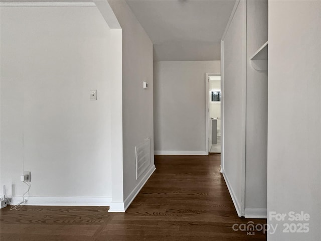 hallway with arched walkways, visible vents, baseboards, and wood finished floors