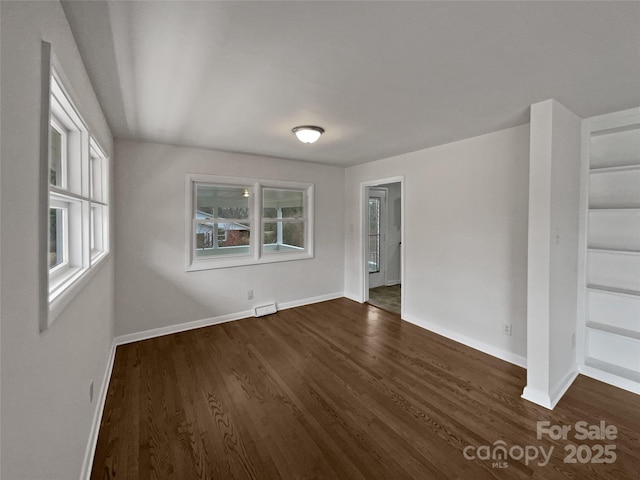 empty room with visible vents, dark wood finished floors, and baseboards