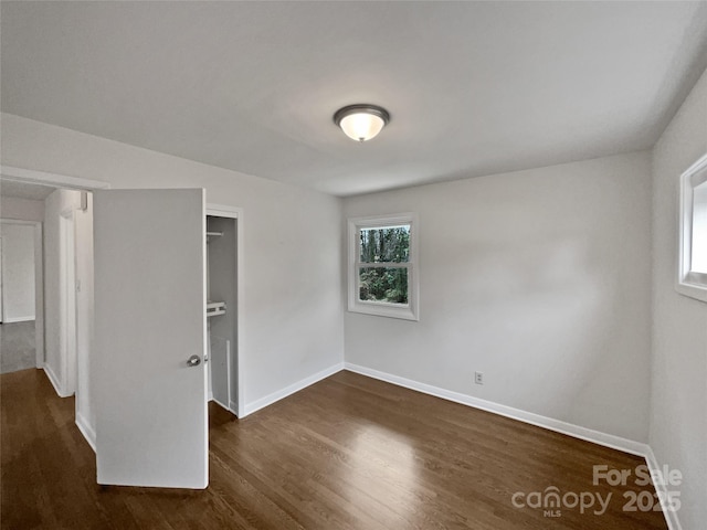 unfurnished room featuring dark wood-style flooring and baseboards