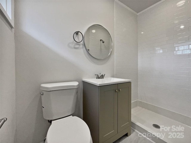 full bathroom with ornamental molding, tiled shower, vanity, and toilet