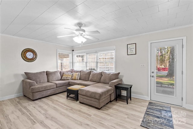 living area with crown molding, light wood-style flooring, a wealth of natural light, and baseboards