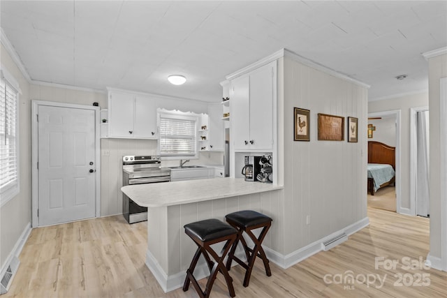 kitchen featuring electric range, a peninsula, light countertops, white cabinetry, and open shelves