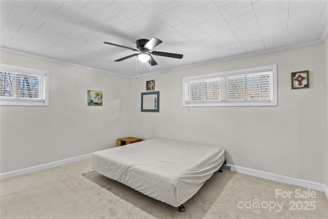 carpeted bedroom with ceiling fan, baseboards, and crown molding