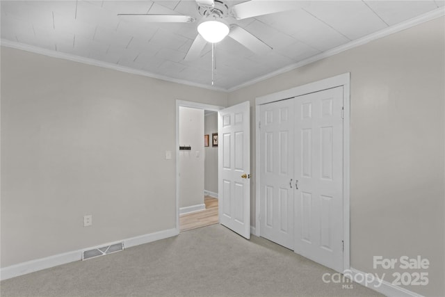 unfurnished bedroom featuring crown molding, baseboards, visible vents, and light colored carpet