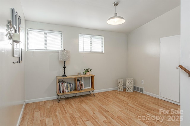 spare room with light wood-type flooring, visible vents, and baseboards