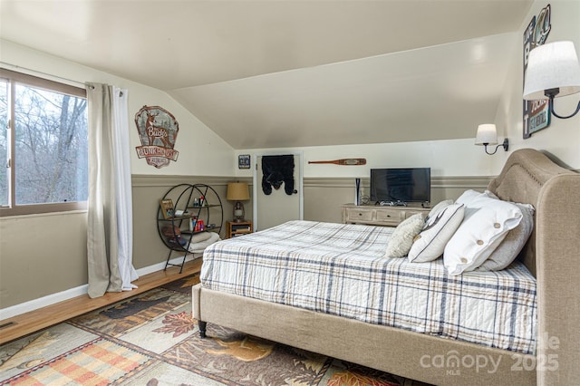 bedroom with baseboards, vaulted ceiling, and wood finished floors