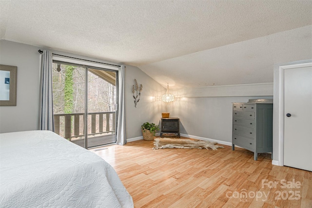 bedroom with baseboards, wood finished floors, access to exterior, vaulted ceiling, and a textured ceiling