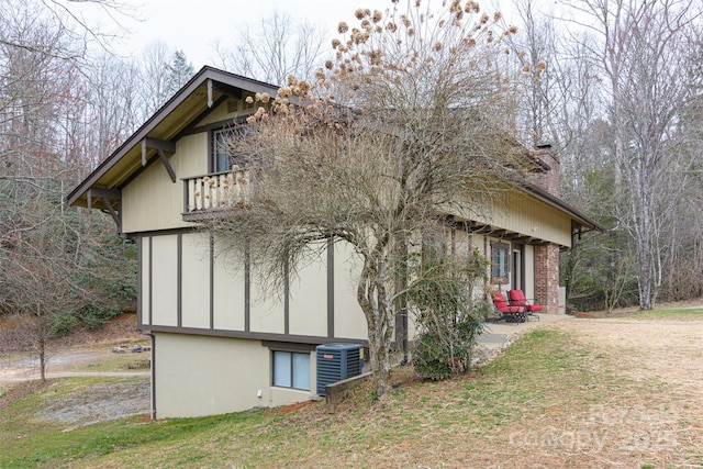 view of side of home with central air condition unit, a balcony, and a chimney