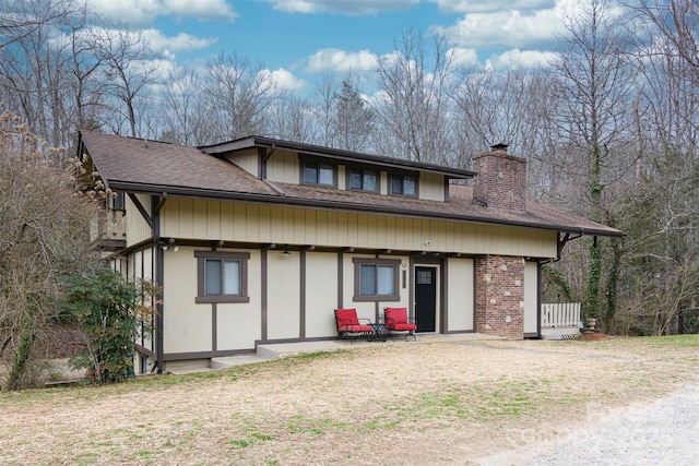 back of house featuring a shingled roof, brick siding, and a chimney