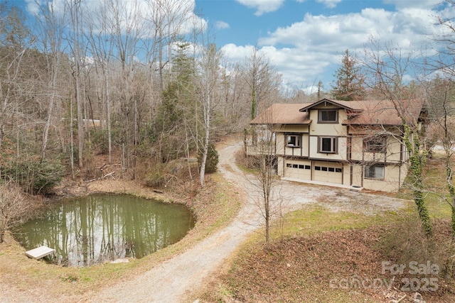 back of property with an attached garage and dirt driveway