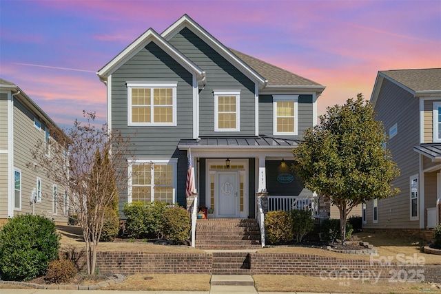 traditional-style home featuring a shingled roof, a standing seam roof, metal roof, and a porch