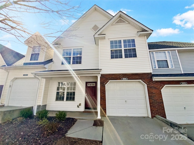 view of property featuring driveway, a garage, and brick siding