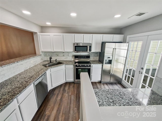 kitchen featuring dark wood finished floors, stainless steel appliances, visible vents, white cabinets, and a sink