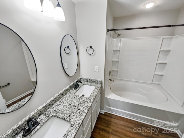 full bathroom with double vanity, wood finished floors, bathtub / shower combination, and a sink