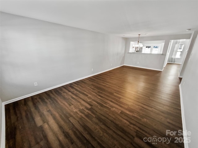 interior space featuring a chandelier, dark wood finished floors, and baseboards