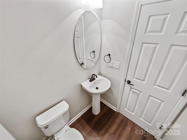 half bath featuring wood finished floors, toilet, and baseboards