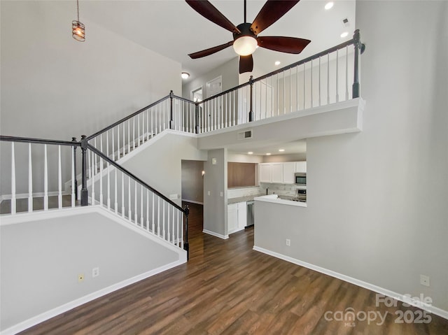 unfurnished living room with visible vents, dark wood finished floors, stairway, and baseboards