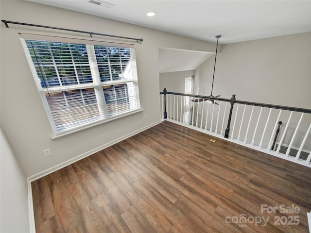 empty room featuring lofted ceiling, recessed lighting, wood finished floors, visible vents, and baseboards