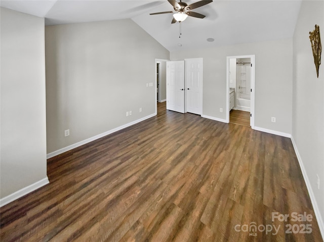 unfurnished bedroom with connected bathroom, dark wood-type flooring, a ceiling fan, baseboards, and vaulted ceiling