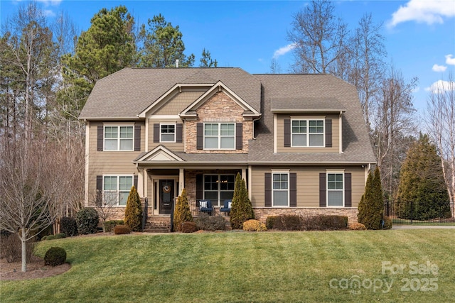 craftsman house with stone siding, a front lawn, covered porch, and roof with shingles