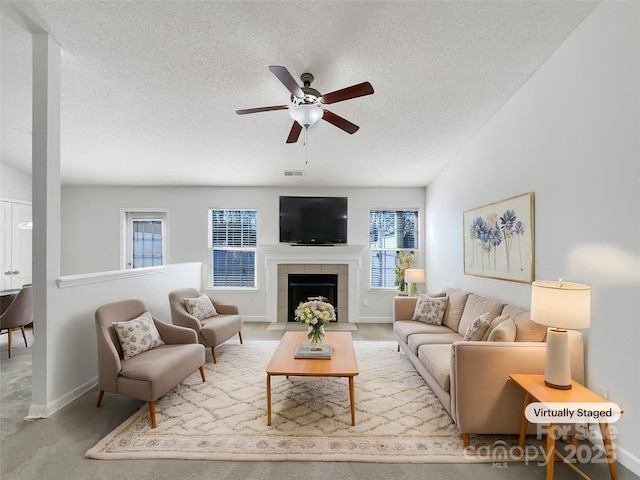 living area with visible vents, a tiled fireplace, a ceiling fan, a textured ceiling, and baseboards