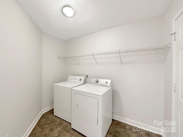 clothes washing area featuring a textured ceiling, laundry area, washing machine and dryer, and baseboards