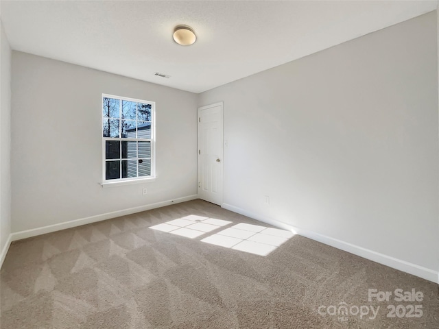 spare room with carpet, visible vents, and baseboards