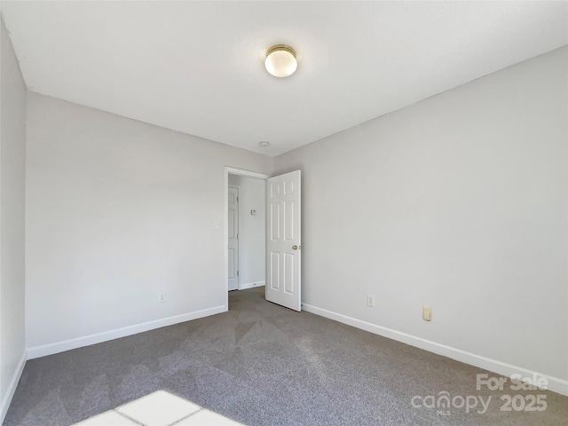 unfurnished room featuring baseboards and dark colored carpet