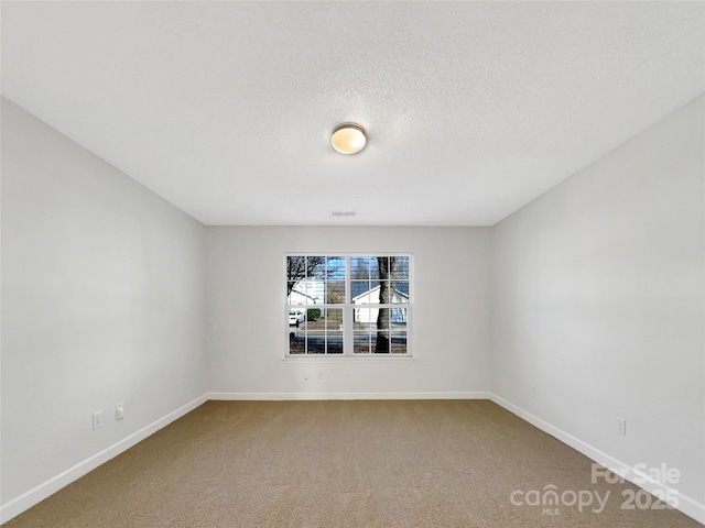 unfurnished room with carpet floors, visible vents, baseboards, and a textured ceiling