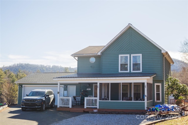 view of front of house featuring driveway, an attached garage, and a sunroom