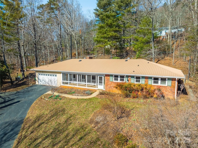 single story home with driveway, an attached garage, metal roof, and brick siding