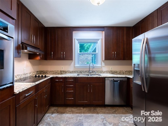 kitchen featuring dark brown cabinetry, light stone counters, stainless steel appliances, under cabinet range hood, and a sink